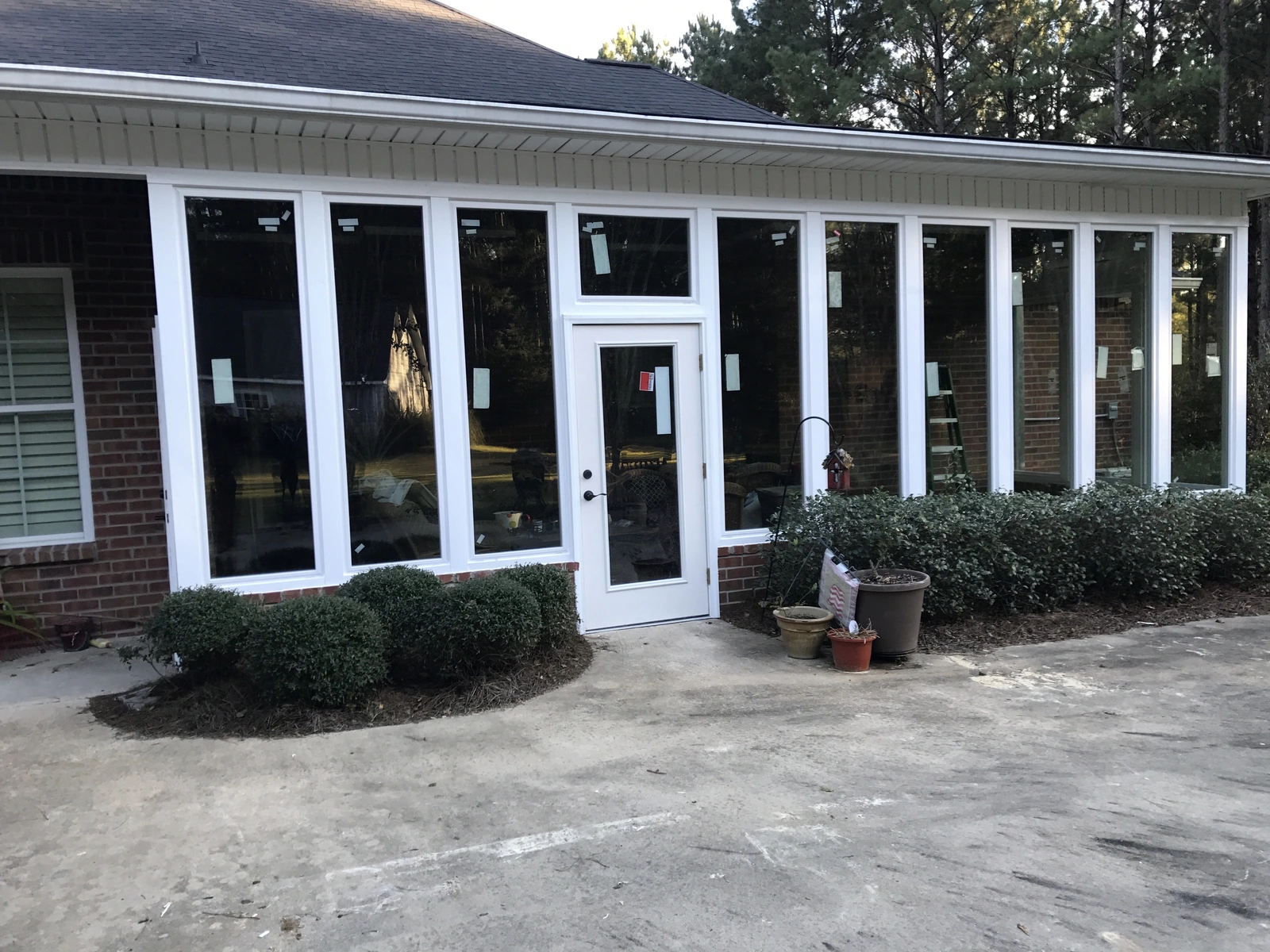 New windows and exterior work — modern entrance with bushes and patio